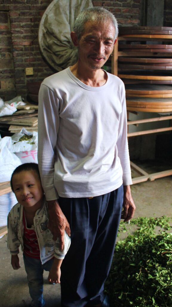 Chinese grandpa and grandson standing with tea and tea equipment surrounding them
