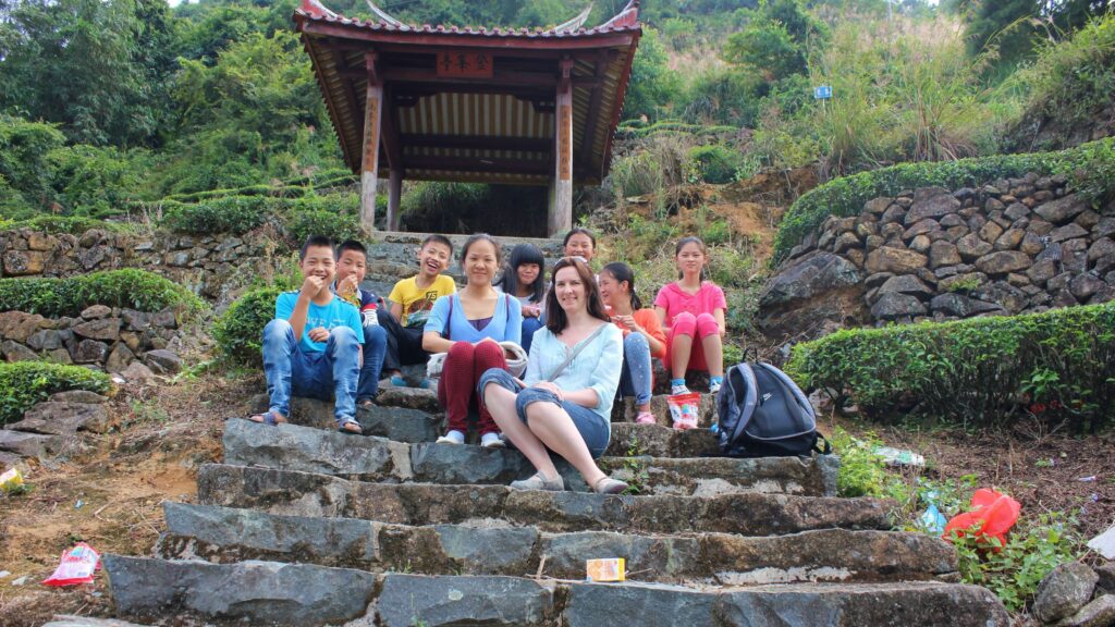 group of people and children on stone steps with small temple structure behind