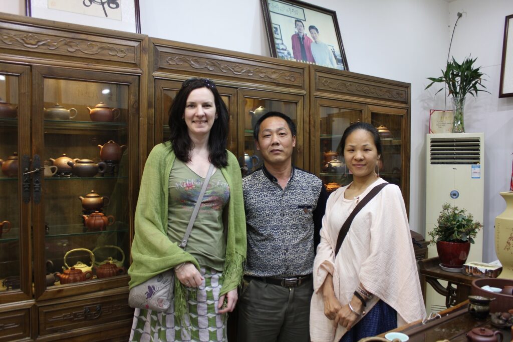 3 people in teahouse standing in front of wooden display cabinets