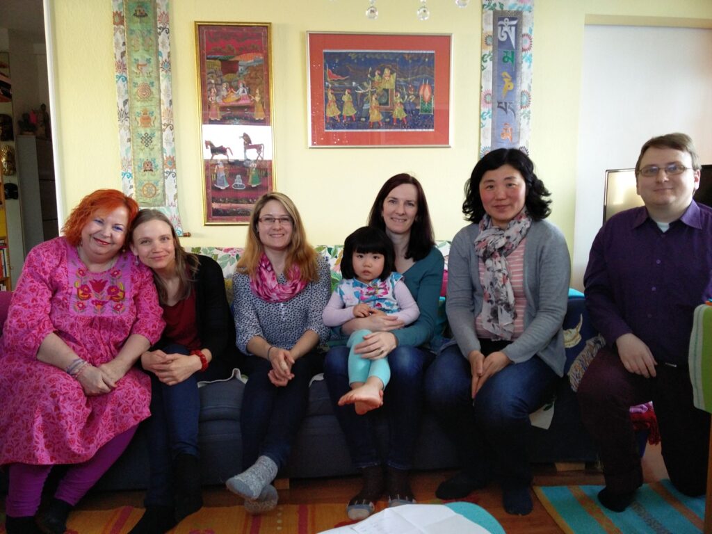 group of people sat facing the camera in a living room