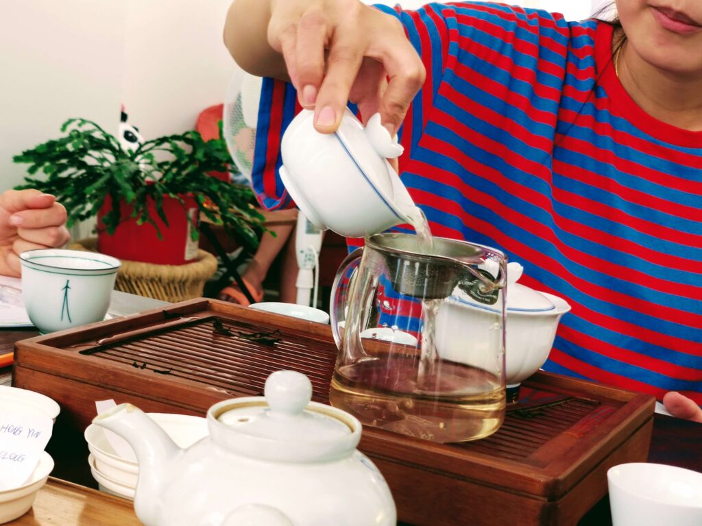 PouringTea_Gaiwan person pouring tea from gaiwan into glass jug