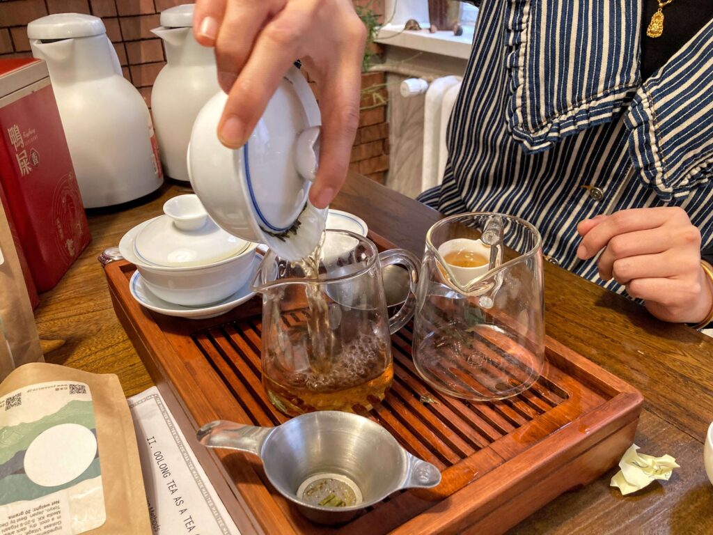 Pouring Duck Shit pouring tea into glass jug, on a tea tray