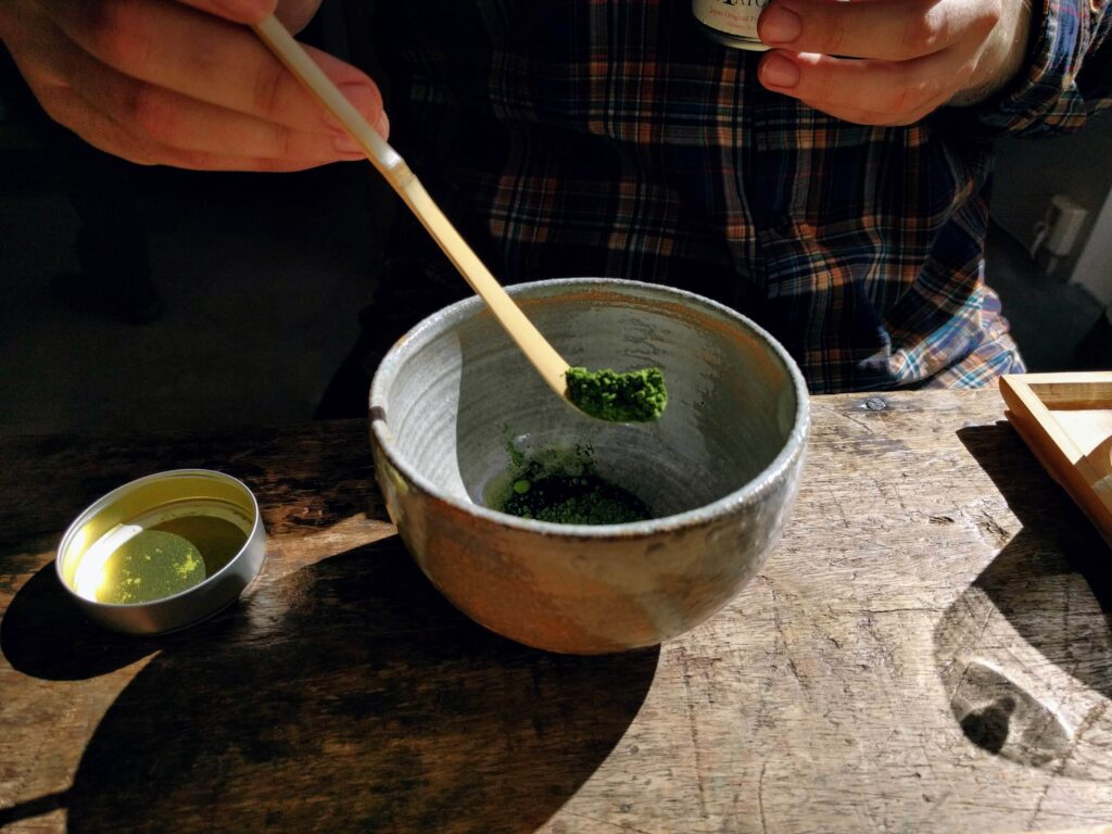 Matcha-measuring measuring matcha with wooden scoop into matcha bowl