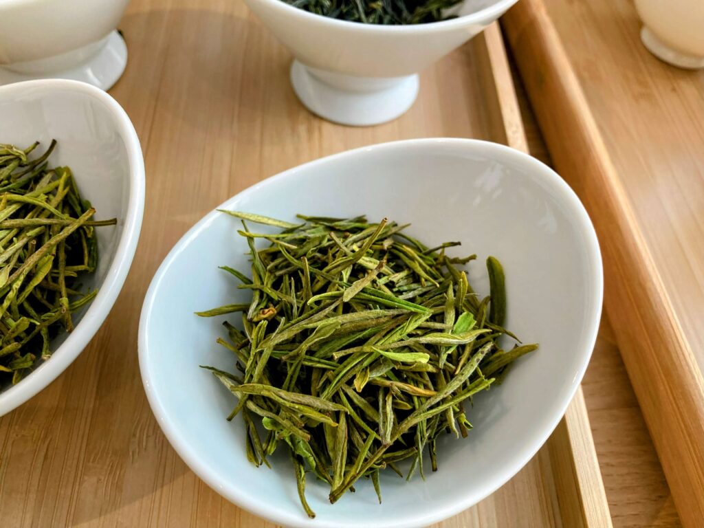 dry green tea leaves in white bowl