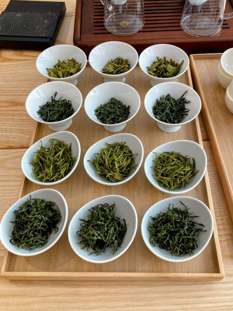 display of 4 different green teas in white pots on wooden tray, 12 pots in total