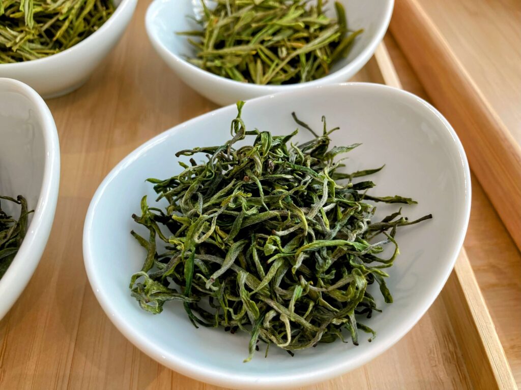 dry green tea leaves in white bowl