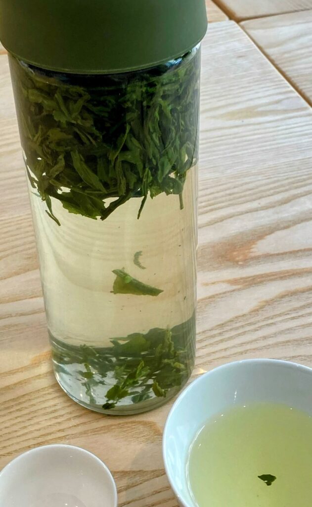 cold brew green tea in glass bottle and white tea cup