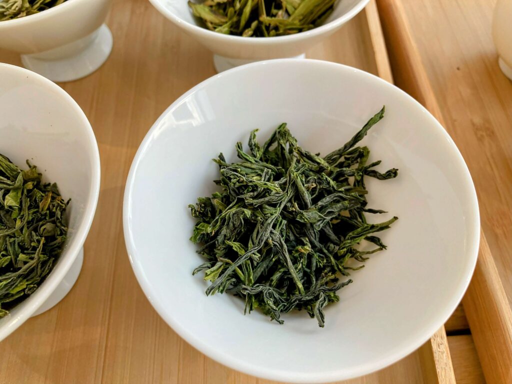 dry green tea leaves in white bowl