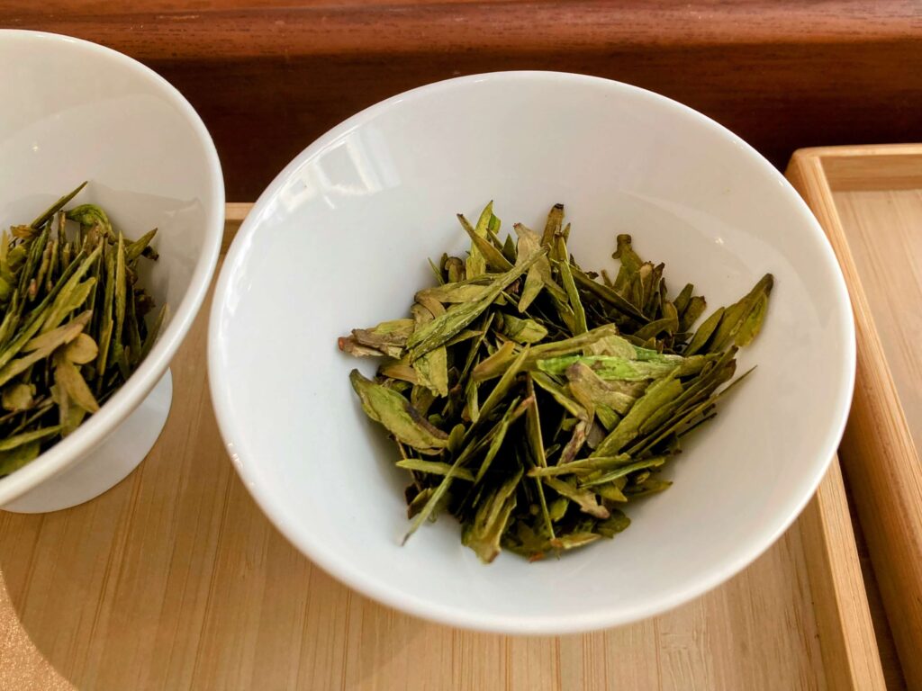 dry green tea leaves in white bowl