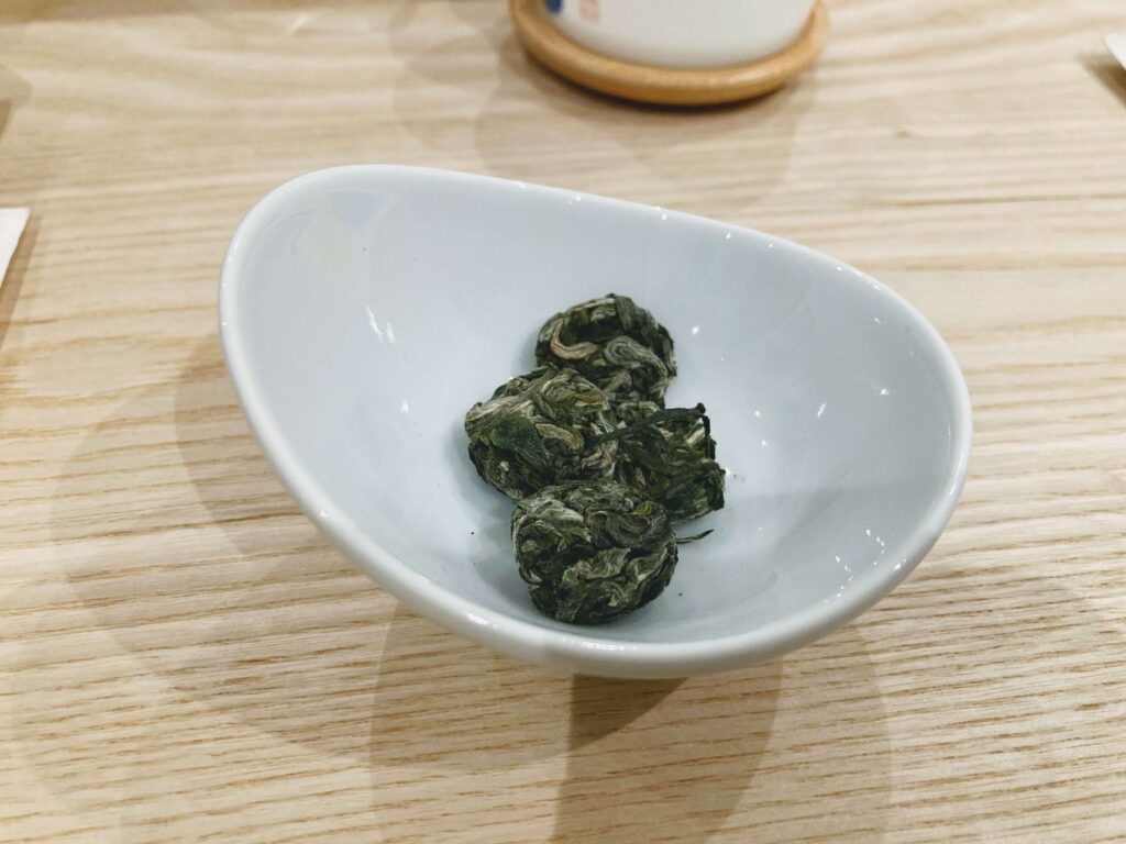 silver coin green tea dry leaves in a bowl