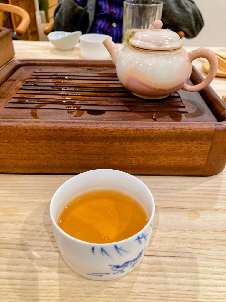 song zhong oolong tea liquor in cup, tea tray behind