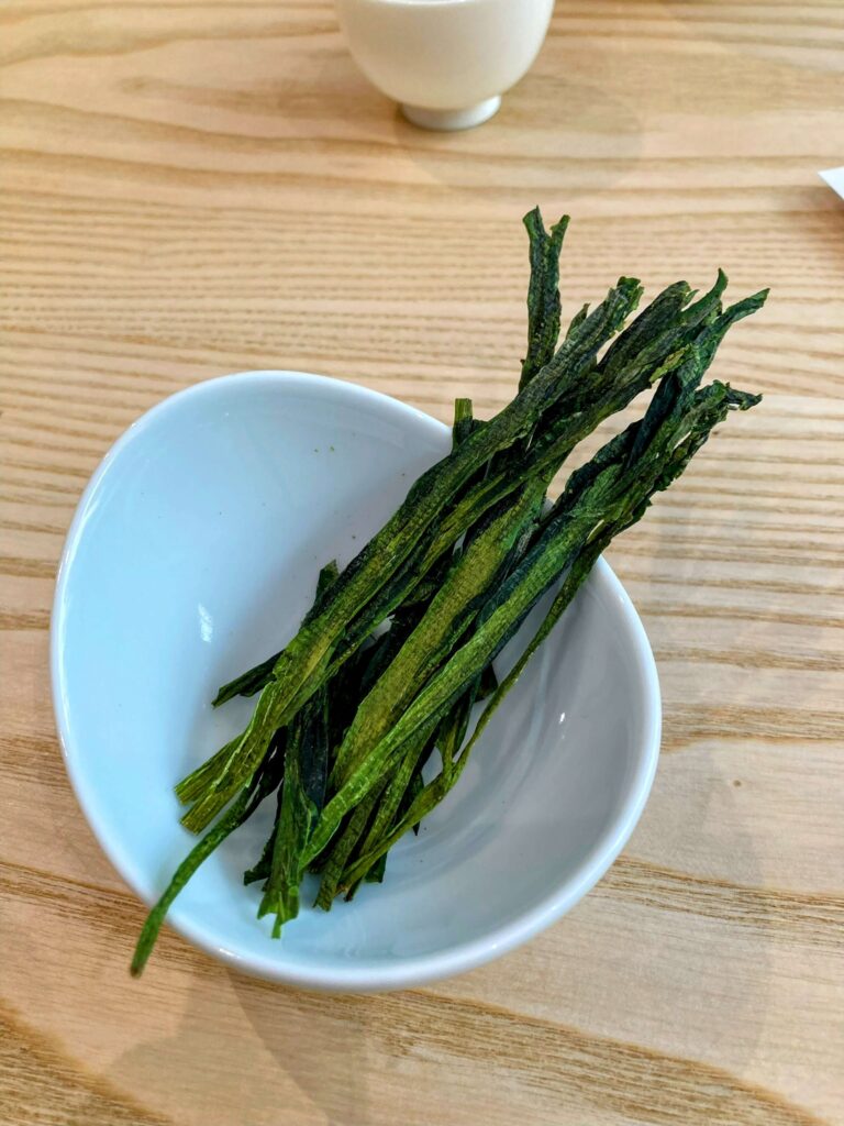 dry green tea leaves in white bowl